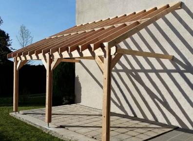 Adossée à la maison, la charpente en bois en kit fait un abri terrasse ou un carport de qualité